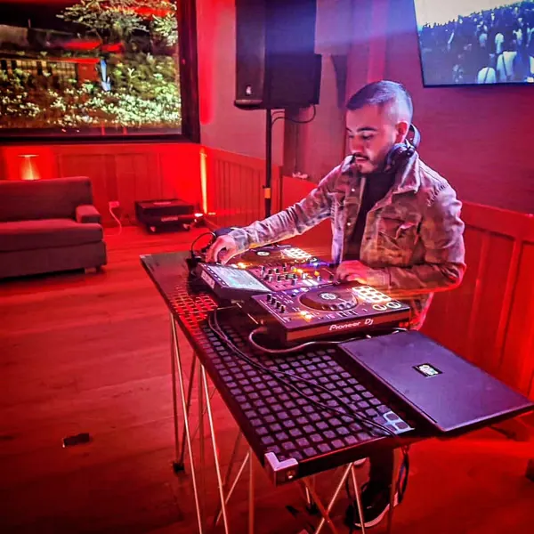 DJ de Live House mezclando en vivo con luces rojas en una fiesta en casa
